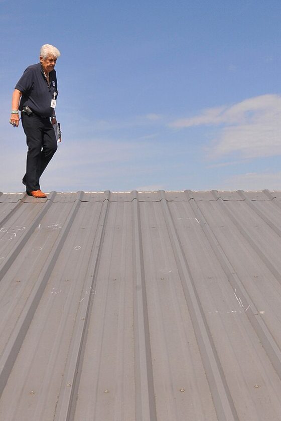 A person walking a ridge on a commercial metal roof