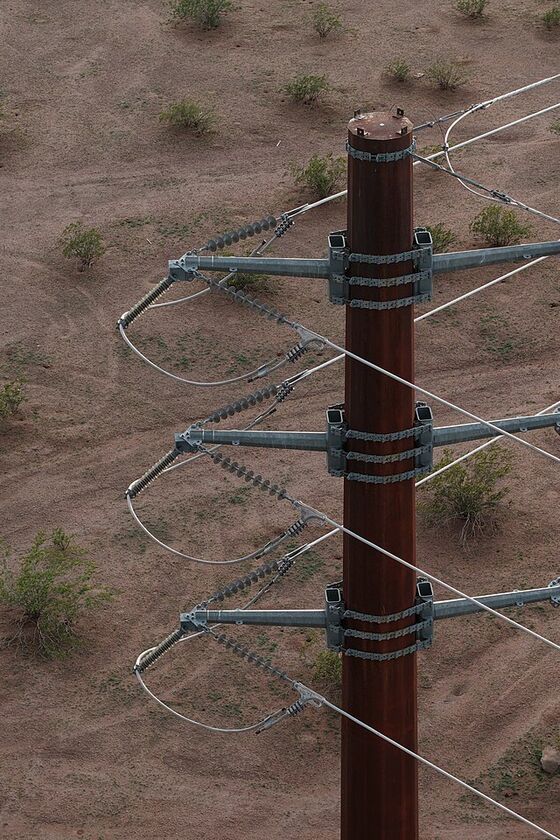 Top of a steel transmission pole with insulators and conductors seen from a drone